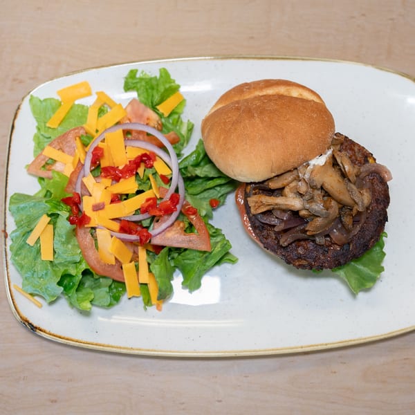 A Home Run Burger with sautéed mushrooms and onions, alongside a fresh garden salad.