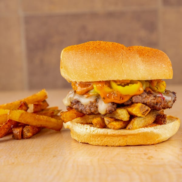 A Home Run Burger with melted cheese, peppers, and fries on a wooden surface.