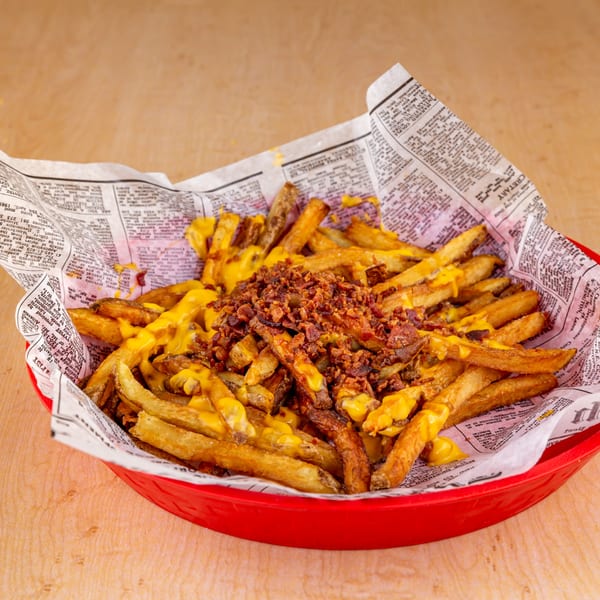 A red basket of Home Run Burger's loaded fries, topped with melted cheese and bacon bits.