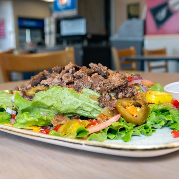 A Home Run Burger salad with ground beef, lettuce, jalapenos, and other toppings on a plate.