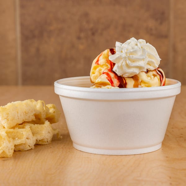Vanilla ice cream with strawberry and caramel syrup, whipped cream, and waffle pieces.