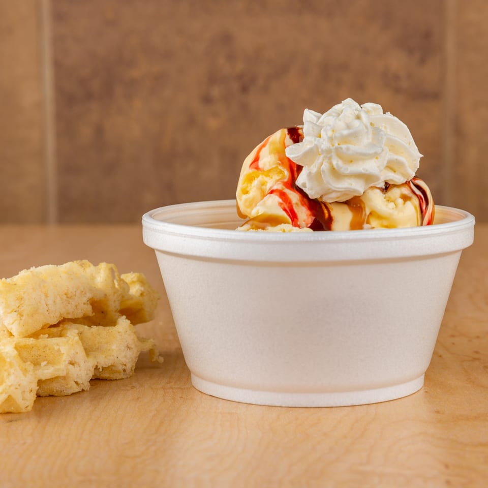 Vanilla ice cream with strawberry and caramel syrup, whipped cream, and waffle pieces.